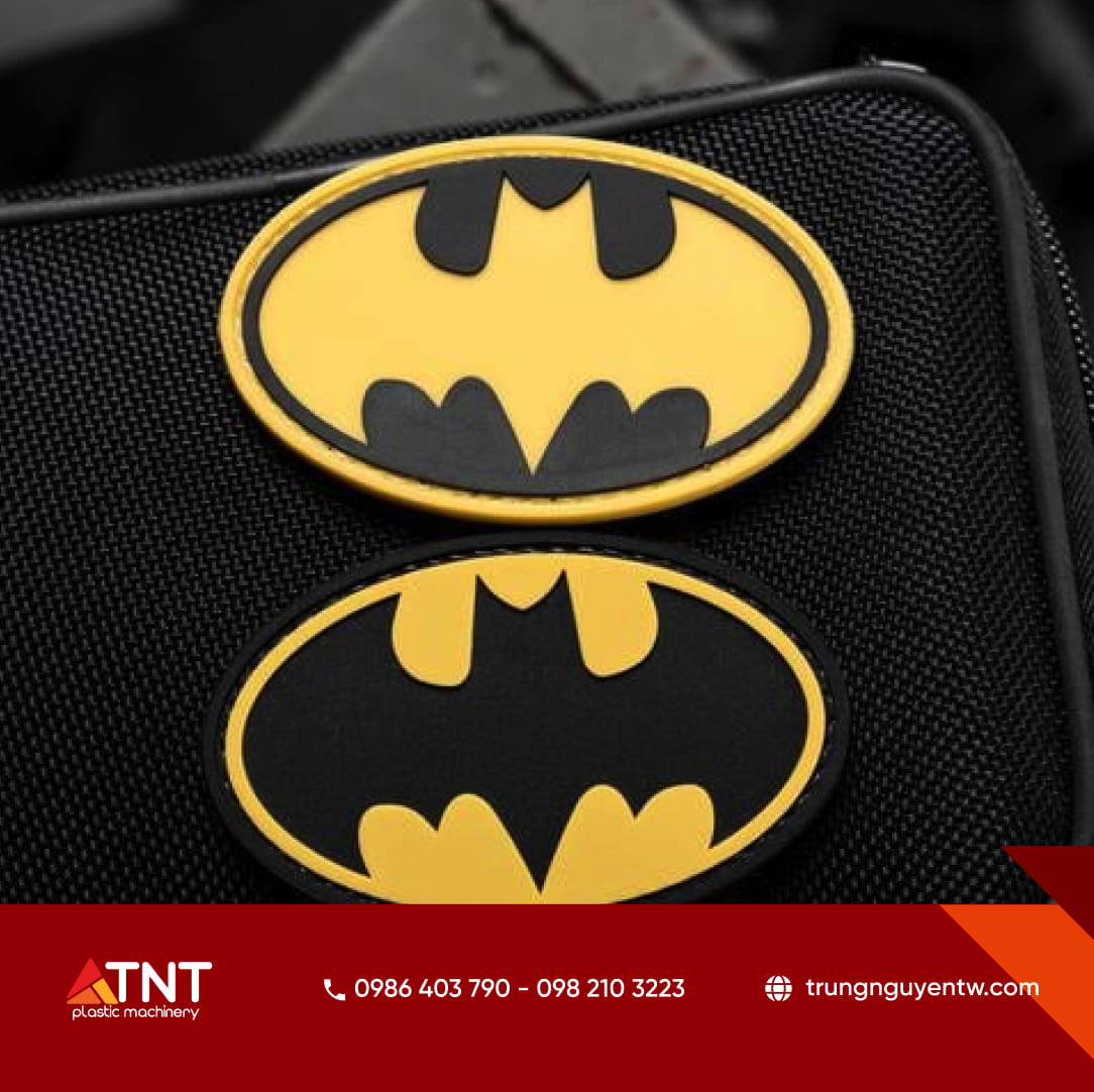 Mẫu logo nhựa dẻo PVC cao cấp dập nổi màu vàng đen, gắn trên nền vải dệt đen